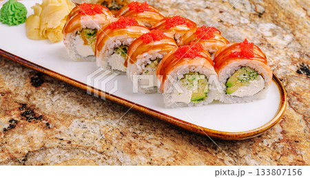 Shrimps sushi rolls with creamy filling and garnishes served on a white plate Shrimps sushi rolls with creamy filling and garnishes served on a white plate 133807156