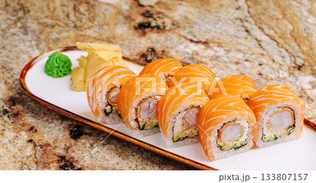 Sushi rolls on a white plate with ginger and wasabi on a marble table Sushi rolls on a white plate with ginger and wasabi on a marble table 133807157