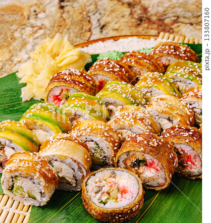 Sushi platter with colorful rolls served on bamboo and garnished with ginger 133807160