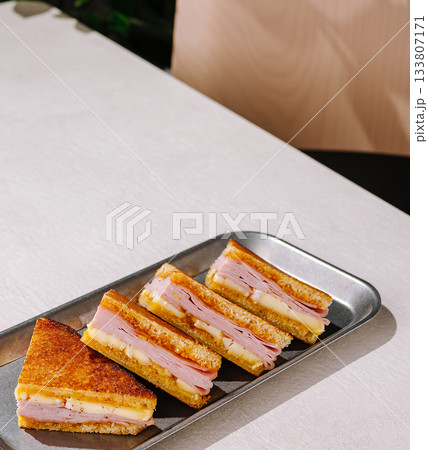 Delightful grilled ham and cheese sandwich slices served on a platter Delightful grilled ham and cheese sandwich slices served on a platter 133807171