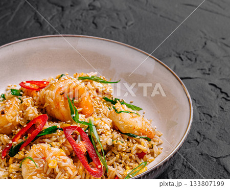 Delicious shrimp fried rice with fresh herbs and chili on a dark background Delicious shrimp fried rice with fresh herbs and chili on a dark background 133807199