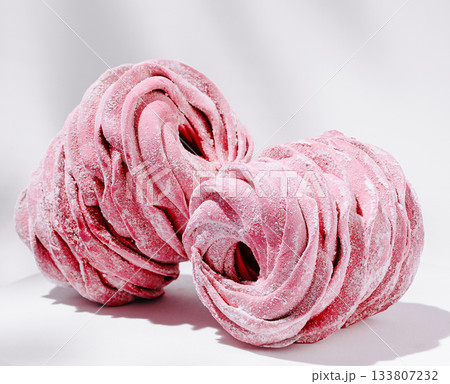 Delicate pink marshmallow cones on display with a soft, elegant background Delicate pink marshmallow cones on display with a soft, elegant background 133807232