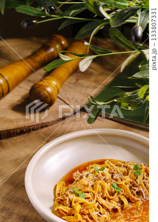 Delicious pasta dish served on a rustic wooden table with olive branches 133807331