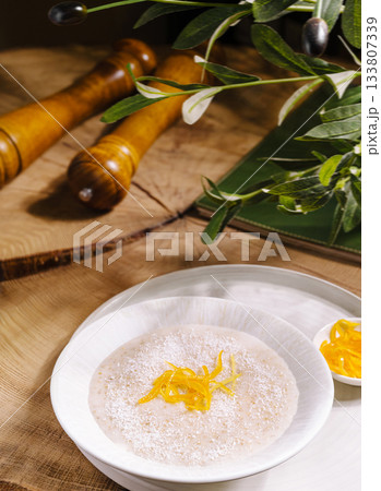 Warm rice pudding garnished with citrus peel on wooden table 133807339