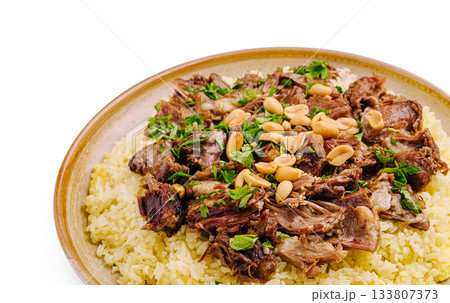 Savory dish of tender meat served on a bed of seasoned rice with herbs and nuts 133807373