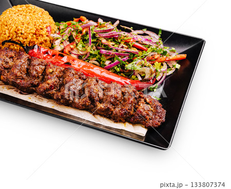 Delicious kebab served with bulgur and fresh salad on black plate Delicious kebab served with bulgur and fresh salad on black plate 133807374