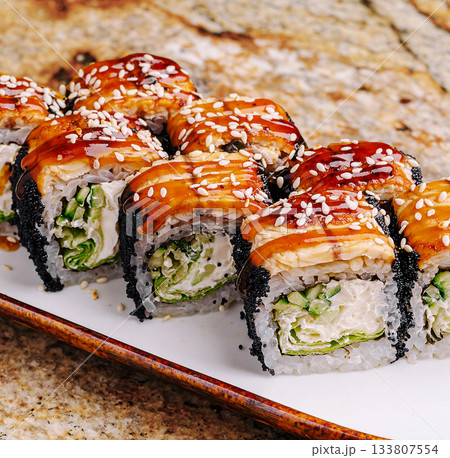 Delicious sushi rolls served on a white plate with sesame seeds on top 133807554