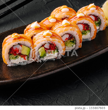 Sushi rolls served on a dark plate with a glossy finish 133807603