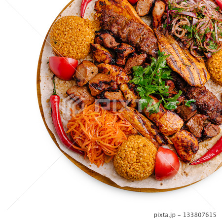 Grilled meat platter with colorful sides served on a round wooden tray 133807615