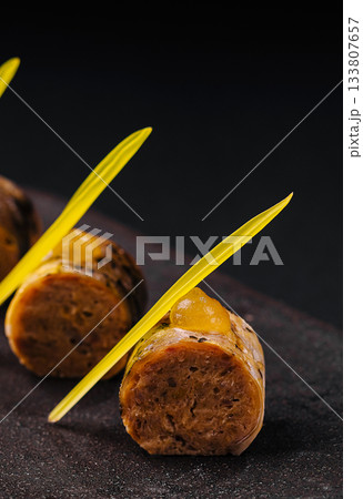 Unique culinary creation with vibrant garnishes on a dark surface 133807657