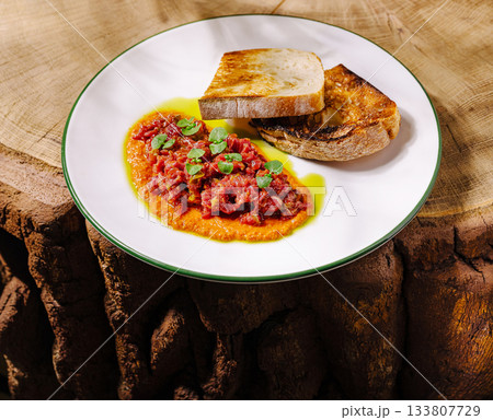 Delicious dish with toasted bread on a rustic wood surface in natural lighting Delicious dish with toasted bread on a rustic wood surface in natural lighting 133807729