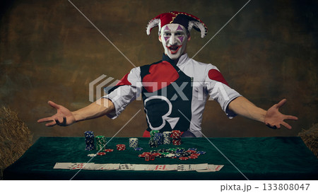 Joker character presenting casino chips and playing cards at gaming table 133808047