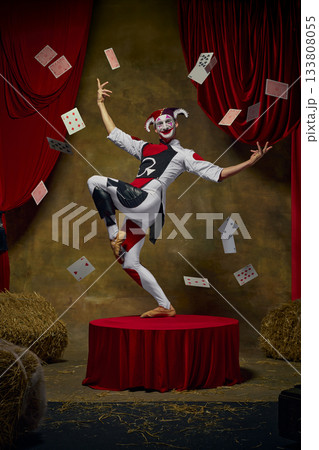 Jester performer on retro stage with flying playing cards. 133808055