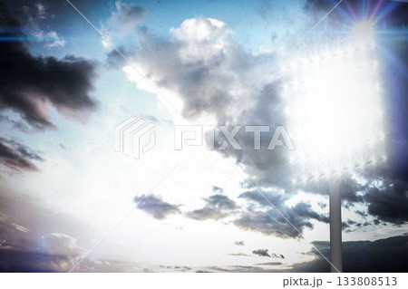 Floodlight tower is illuminating evening sky in flat design, with bright lamps and cloud textures 133808513