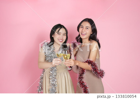 New Year celebration. Two friends toasting with champagne and wearing festive decorations. 133810054