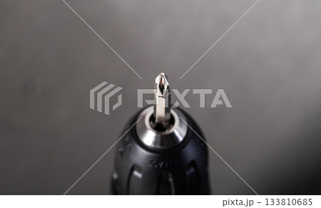 Close up view of shining metal Phillips head screwdriver bit in drill chuck, essential tool for fastening tasks 133810685