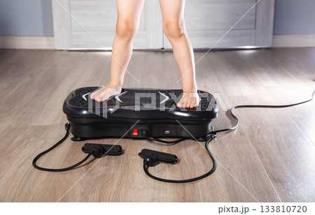 Child's legs on a sports vibration platform at home, close-up, sports simulator 133810720