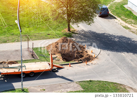 A dug hole in the city near the road. Concept of works on elimination of water channel leakage, laying pipes, repair works in the water supply system. Copy space for text 133810721