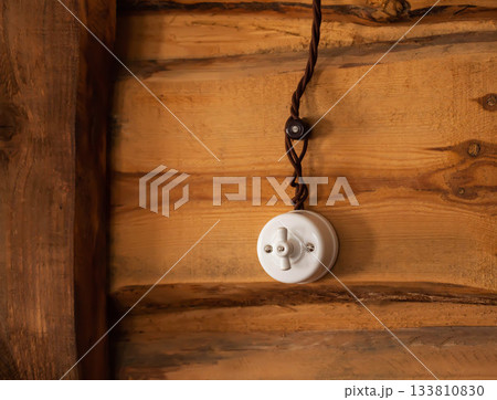 old retro style electrical switch on a log wooden wall in the village, close-up. Copy space for text old retro style electrical switch on a log wooden wall in the village, close-up. Copy space for text 133810830