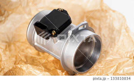 Modern electronic mass air flow sensor on brown paper, close-up. Car spare part, industry Modern electronic mass air flow sensor on brown paper, close-up. Car spare part, industry 133810834