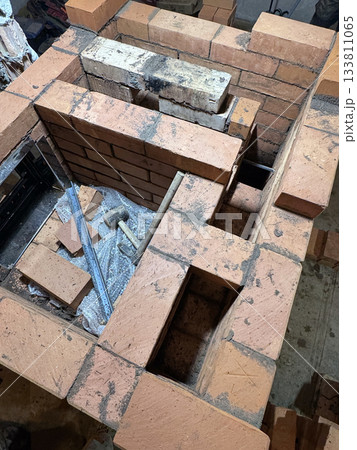 Brickwork of a heating stove. Channels for dividing and passing smoke. Cooking plate. Close-up. 133811065