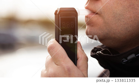 Side View Of Man Taking Breathalyzer Test. Driver Checking For Alcohol Intoxication Level. 133811335
