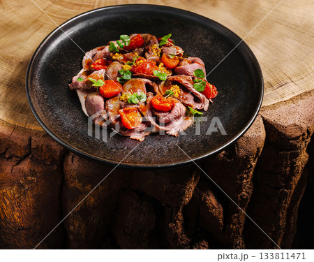 Sliced roast beef with tomatoes served on a rustic wooden table 133811471