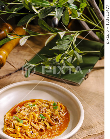 Delicious homemade pasta with rich sauce and fresh herbs on a rustic table Delicious homemade pasta with rich sauce and fresh herbs on a rustic table 133811477