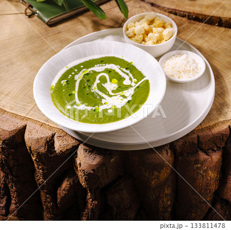 Creamy green soup served with crunchy toppings on a rustic wooden table Creamy green soup served with crunchy toppings on a rustic wooden table 133811478