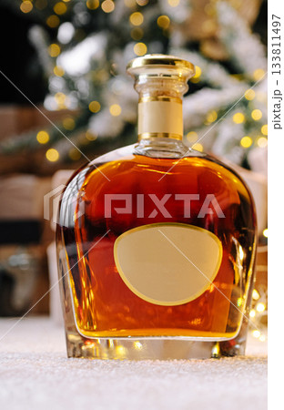 Elegant glass decanter filled with amber liquid beside holiday decorations 133811497