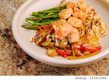 Salmon with noodles and vegetables served in a round bowl Salmon with noodles and vegetables served in a round bowl 133811499