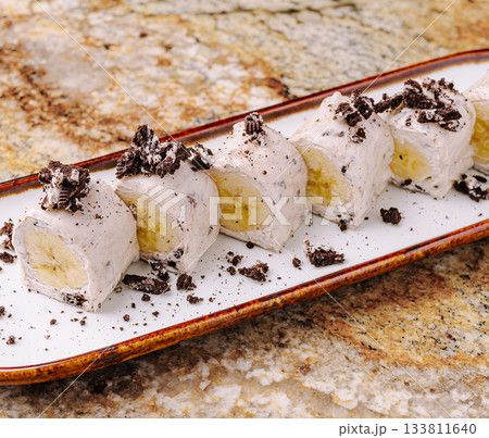 Delicious dessert with rolled ice cream and banana served on a plate 133811640