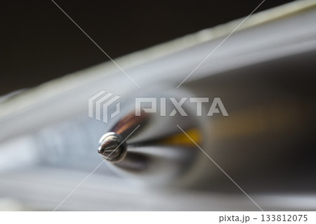 A shiny silver pen rests on an open notebook, ready for use. 133812075