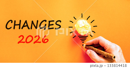 Changes 2026 symbol. Concept words Changes 2026 on beautiful orange paper. Beautiful orange paper background. Light bulb icon. Businessman's hand with pen. Business changes 2026 concept. Copy space 133814418