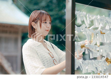 おみくじを結ぶ女性の参拝シーン おみくじを結ぶ女性の参拝シーン 133814547