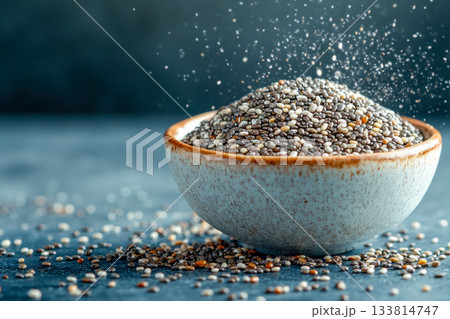 A bowl filled with chia seeds is surrounded by scattered seeds, showcasing a clean and healthy lifestyle choice in natural light A bowl filled with chia seeds is surrounded by scattered seeds, showcasing a clean and healthy lifestyle choice in natural light 133814747