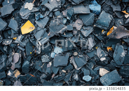 Small fragments of black, blue, and yellow materials are scattered in an industrial area, showcasing various textures and colors Small fragments of black, blue, and yellow materials are scattered in an industrial area, showcasing various textures and colors 133814835