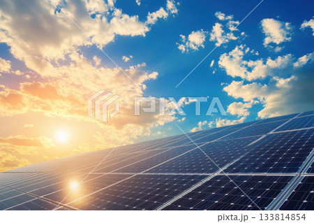 Rows of solar panels shine as the sun sets, creating a beautiful contrast against a blue sky filled with clouds Rows of solar panels shine as the sun sets, creating a beautiful contrast against a blue sky filled with clouds 133814854