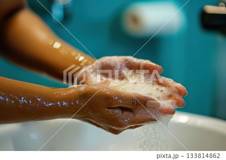 Hands covered in soap bubbles are being washed in a clean bathroom sink, showcasing proper hygiene practices in daily life 133814862