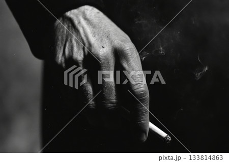 A close-up view shows a hand gripping a cigarette, smoke swirling in the air, capturing a moment of contemplation and solitude A close-up view shows a hand gripping a cigarette, smoke swirling in the air, capturing a moment of contemplation and solitude 133814863