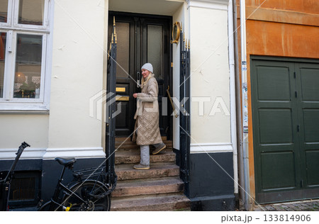 woman entering old townhouse doorway in winter clothing woman entering old townhouse doorway in winter clothing 133814906