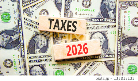 Taxes 2026 new year symbol. Concept words Taxes 2026 on beautiful wooden blocks. Beautiful dollar bills background. Dollar bills. Business and taxes 2026 new year concept. Copy space. Taxes 2026 new year symbol. Concept words Taxes 2026 on beautiful wooden blocks. Beautiful dollar bills background. Dollar bills. Business and taxes 2026 new year concept. Copy space. 133815133