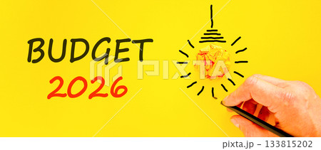 Budget 2026 symbol. Concept words Budget 2026 on beautiful yellow paper. Beautiful orange paper background. Light bulb icon. Businessman's hand with pen. Business and budget 2026 concept. Copy space. Budget 2026 symbol. Concept words Budget 2026 on beautiful yellow paper. Beautiful orange paper background. Light bulb icon. Businessman's hand with pen. Business and budget 2026 concept. Copy space. 133815202