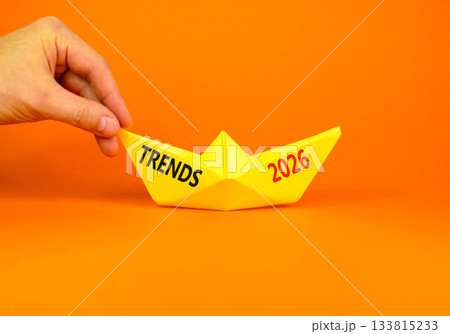 Trends 2026 new year symbol. Concept words Trends 2026 on beautiful yellow paper boat. Beautiful orange paper background. Businessman's hand. Business and Trends 2026 new year concept. Copy space. 133815233