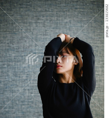 暗い背景の前でポーズをとる若い女性 133815682