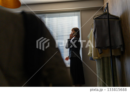 ブラインド越しの光の中、職場で電話するスーツ姿の女性 ブラインド越しの光の中、職場で電話するスーツ姿の女性 133815688