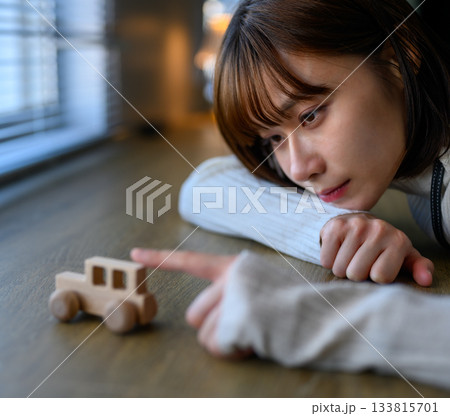 おもちゃの木製車を見つめる若い女性のクローズアップ おもちゃの木製車を見つめる若い女性のクローズアップ 133815701