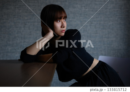 テーブルに肘をついて物思いにふける若い女性 テーブルに肘をついて物思いにふける若い女性 133815712