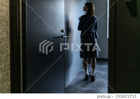 暗い廊下でドアの前に佇む女性の後ろ姿 133815713