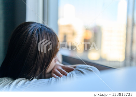 窓辺で街を見つめる若い女性の横顔 133815723